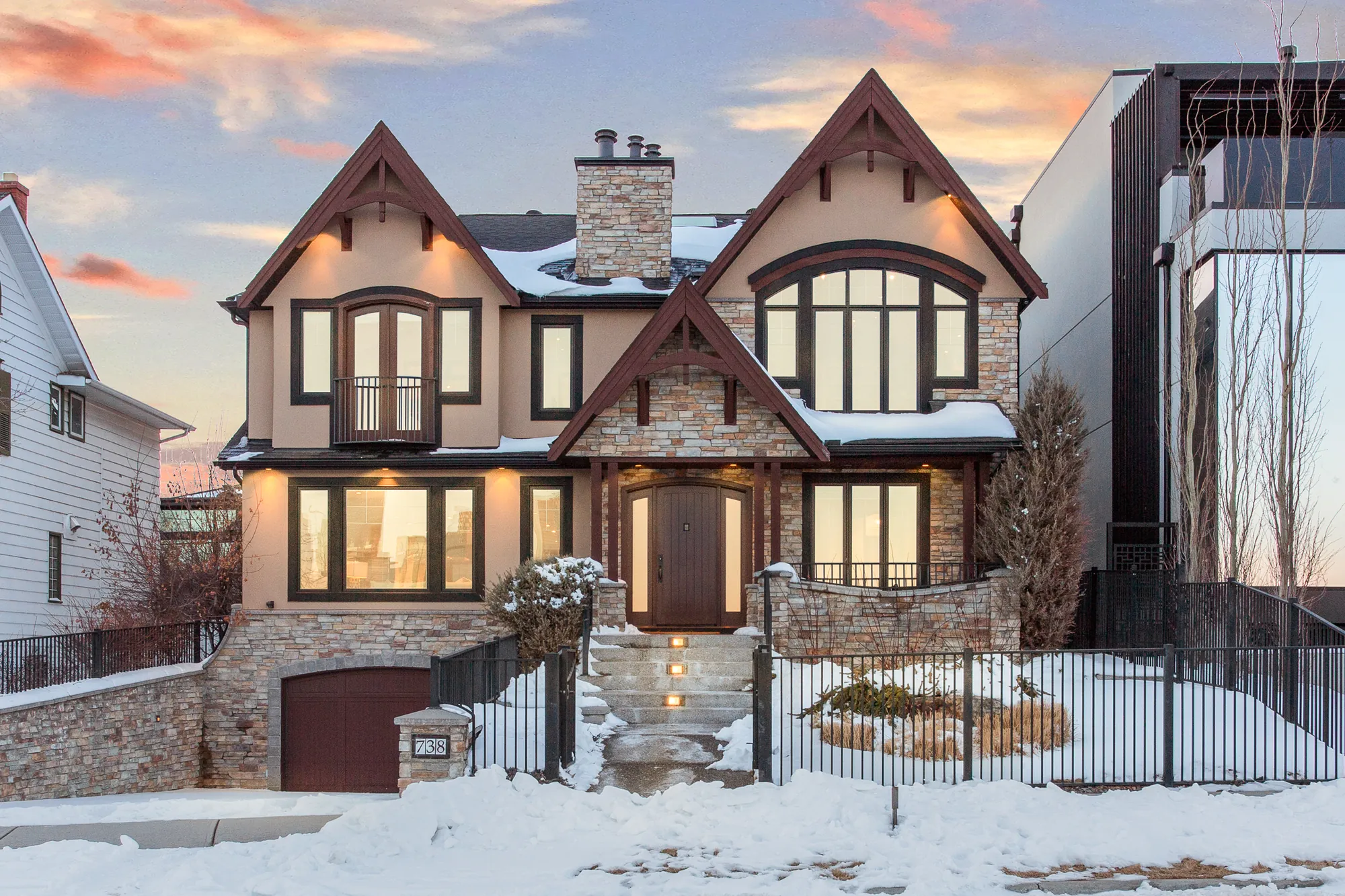 Front elevation at twilight with stone, timber gables and lit windows